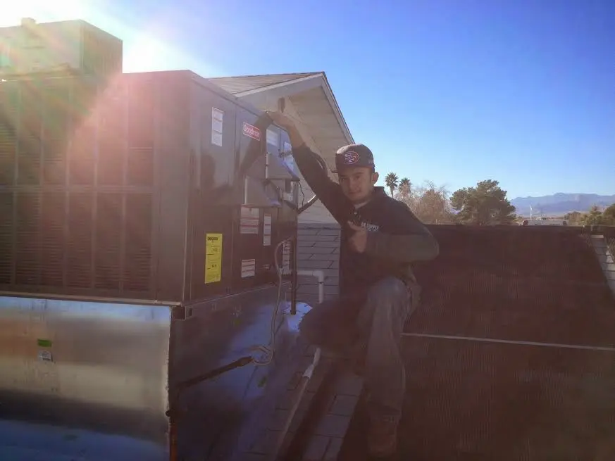 HVAC technician performing HVAC Inspection on a rooftop unit in Milo