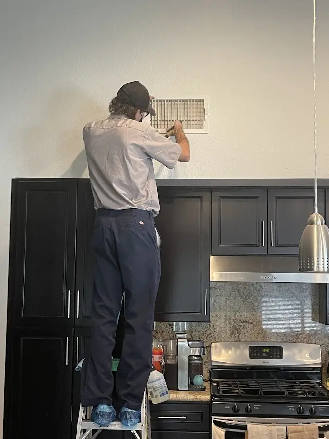 Technician inspecting an air vent during HVAC service in Milo